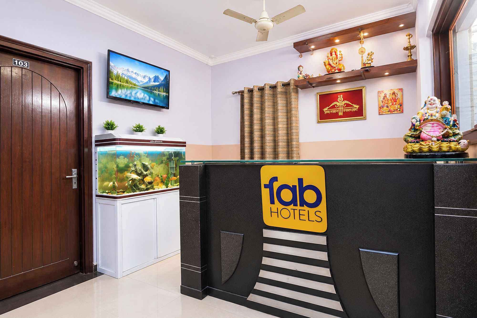 Un comptoir d’accueil d’hôtel agrémenté d’un aquarium, d’un téléviseur et de statues religieuses.