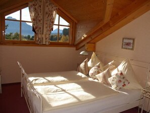 A bedroom with a bed, a window with curtains, a lamp, and a picture on the wall. - Aggenstein House Mountain View (Rieden am Forggensee)