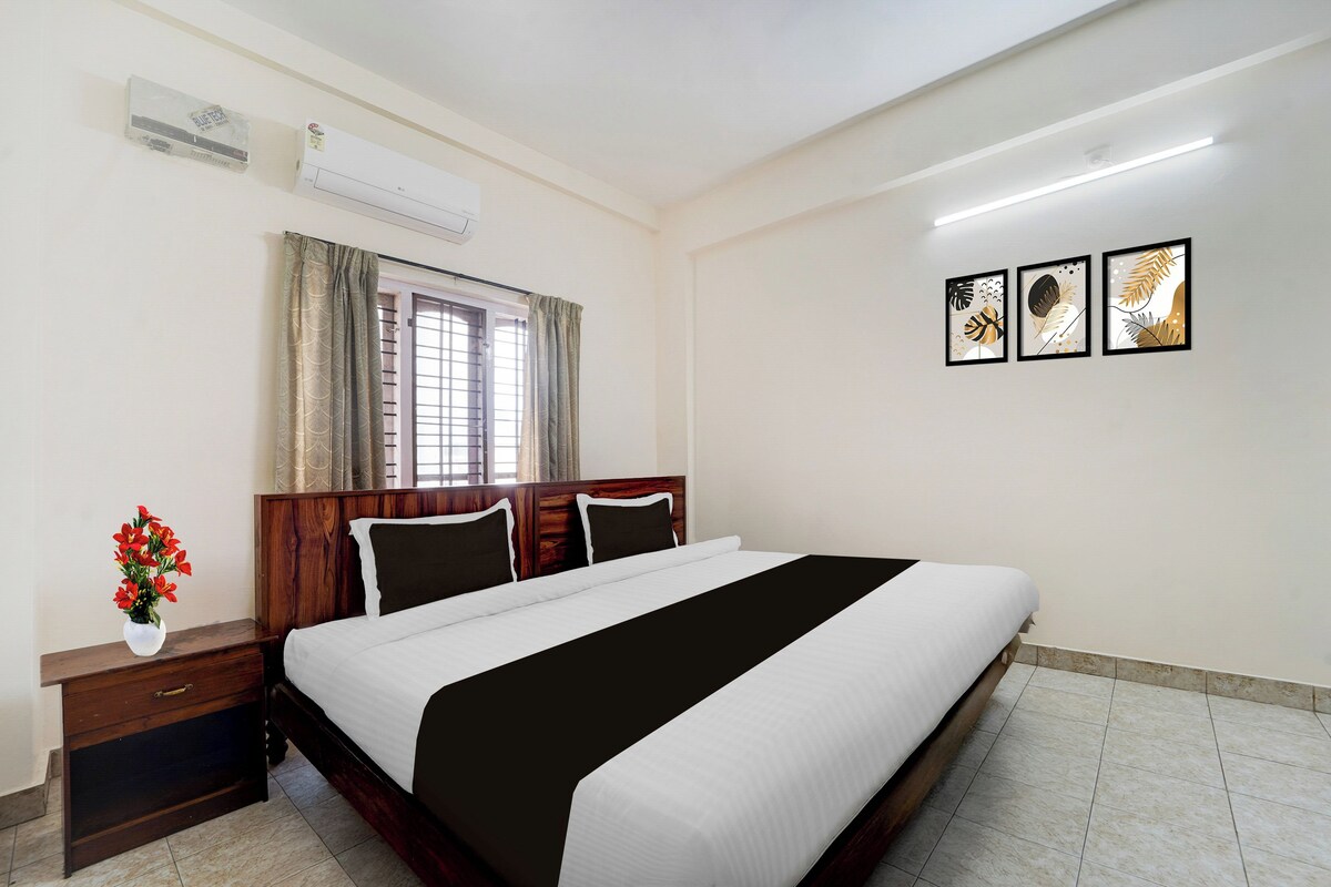 A hotel room with a bed, bedside table, and a window with curtains.