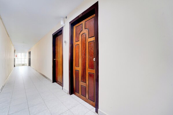 A hallway with two wooden doors, white walls, and a tiled floor.