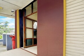 A building entrance with a closed shutter, a red fire hydrant, and a clear sky.