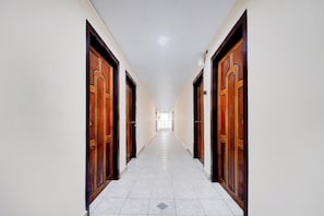 A corridor with doors on both sides, leading to a bright room at the end.