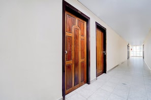 Un pasillo con dos puertas de madera y piso de baldosas.