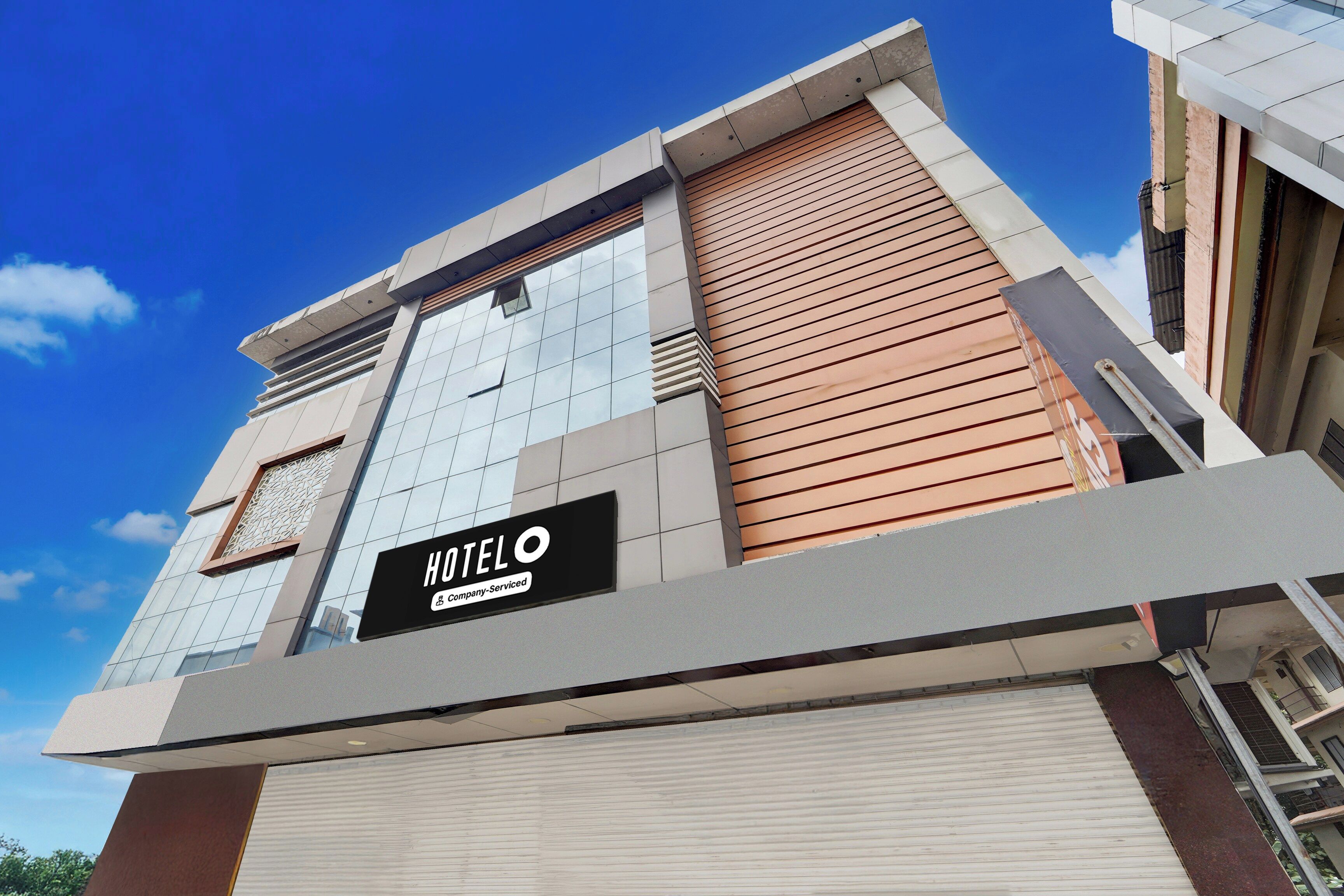 A modern hotel building with a prominent sign indicating it is company-serviced.