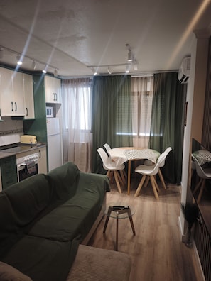 Un espacio habitable compacto con kitchenette, comedor y zona de estar.