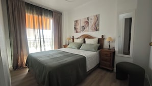 Ein Schlafzimmer mit Bett, Nachttischen, einer Lampe, einem Fenster mit Vorhängen und einem Bild an der Wand.