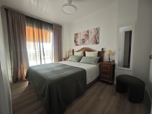 Una camera da letto con un letto, comodini, una lampada, una finestra con tende e un quadro appeso al muro.
