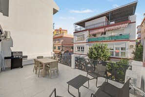 Terrassa exterior amb una barbacoa, taula de menjador i cadires.
