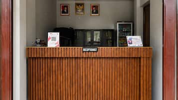 A reception desk with a wooden finish, a sign labeled 'RECEPTIONIST,' and three framed pictures above it.