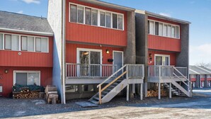 A two-story building with a red exterior, balconies, and a staircase leading to the upper floor. - 2-Level Cabin @ Scribners | Huge Spa & 3 Balconies (Tannersville)