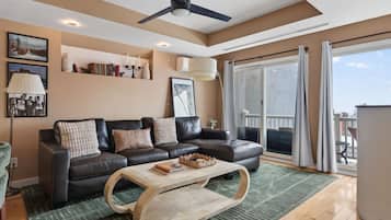 A modern living room with a leather sofa, a wooden coffee table, and a large sliding glass door leading to a balcony.