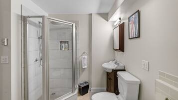 Een moderne badkamer met een douchecabine van glas, een toilet en een wastafel.