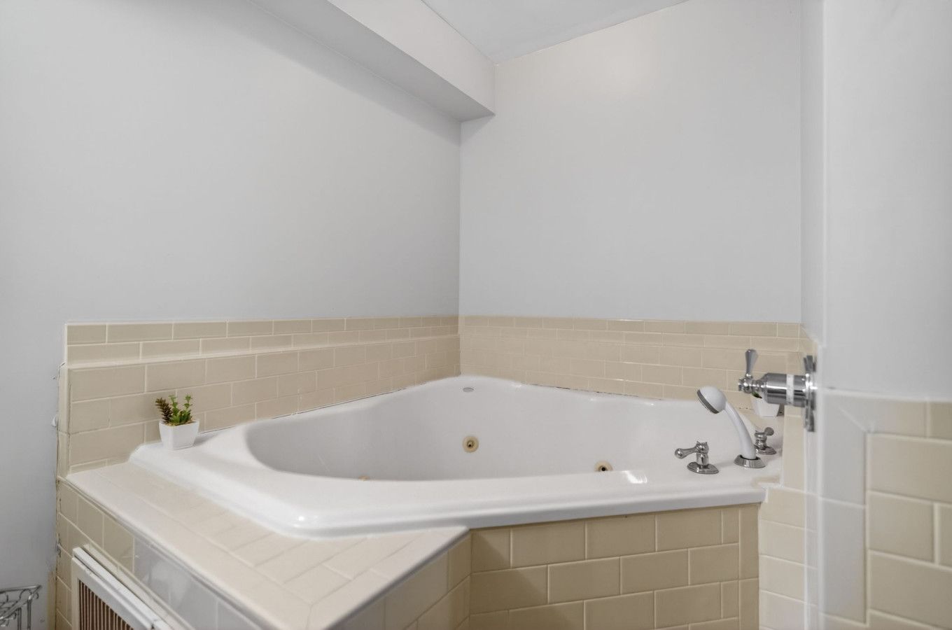 A modern bathroom with a freestanding bathtub, a small potted plant, and a towel rack.