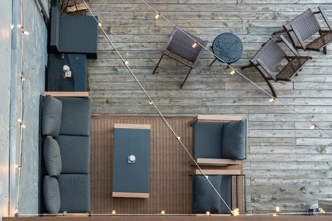 Un espace extérieur aménagé avec un canapé, deux fauteuils et une petite table, le tout disposé sur une terrasse en bois.