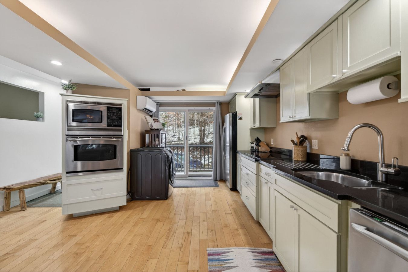 Una cocina moderna con electrodomésticos de acero inoxidable, encimera negra y vistas al exterior.