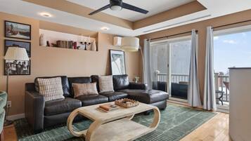 Un salon moderne avec un canapé en cuir, une table basse en bois et une grande porte-fenêtre coulissante donnant sur un balcon.