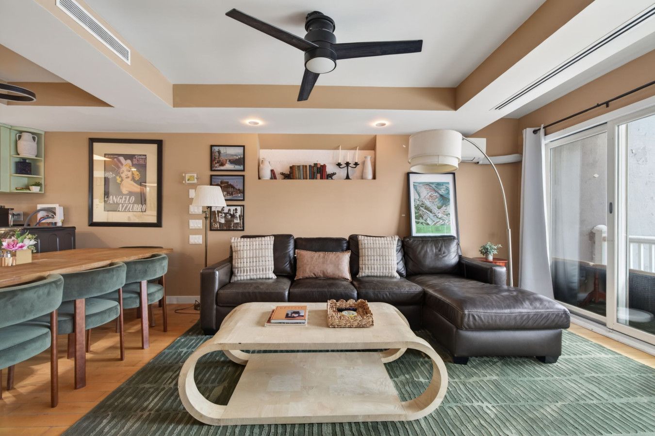 A modern living room with a sectional sofa, a dining table, and a ceiling fan.