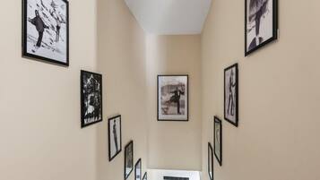 A hallway with framed pictures on the walls, leading to a room with a white door.