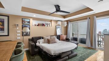 A modern bedroom with a bed, a desk, and a balcony.