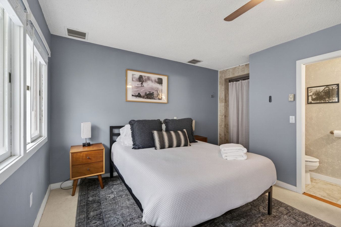 A bedroom with a bed, bedside table, and a framed picture on the wall.