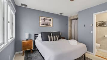 A bedroom with a bed, bedside table, and a framed picture on the wall.