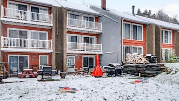 Ein mehrstöckiges Wohngebäude mit Balkonen, einem Grillplatz und einem verschneiten Hof.