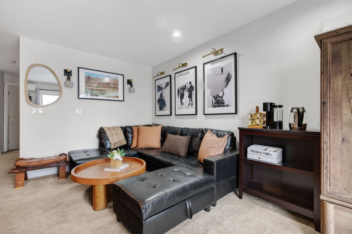 A modern living room with a sectional sofa, a round coffee table, and a bookshelf.