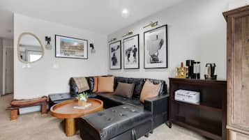 A modern living room with a sectional sofa, a round coffee table, and a bookshelf.