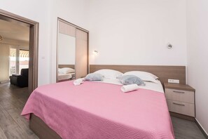 Ein Hotelzimmer mit Bett, Nachttisch, Spiegel und Blick ins Freie.