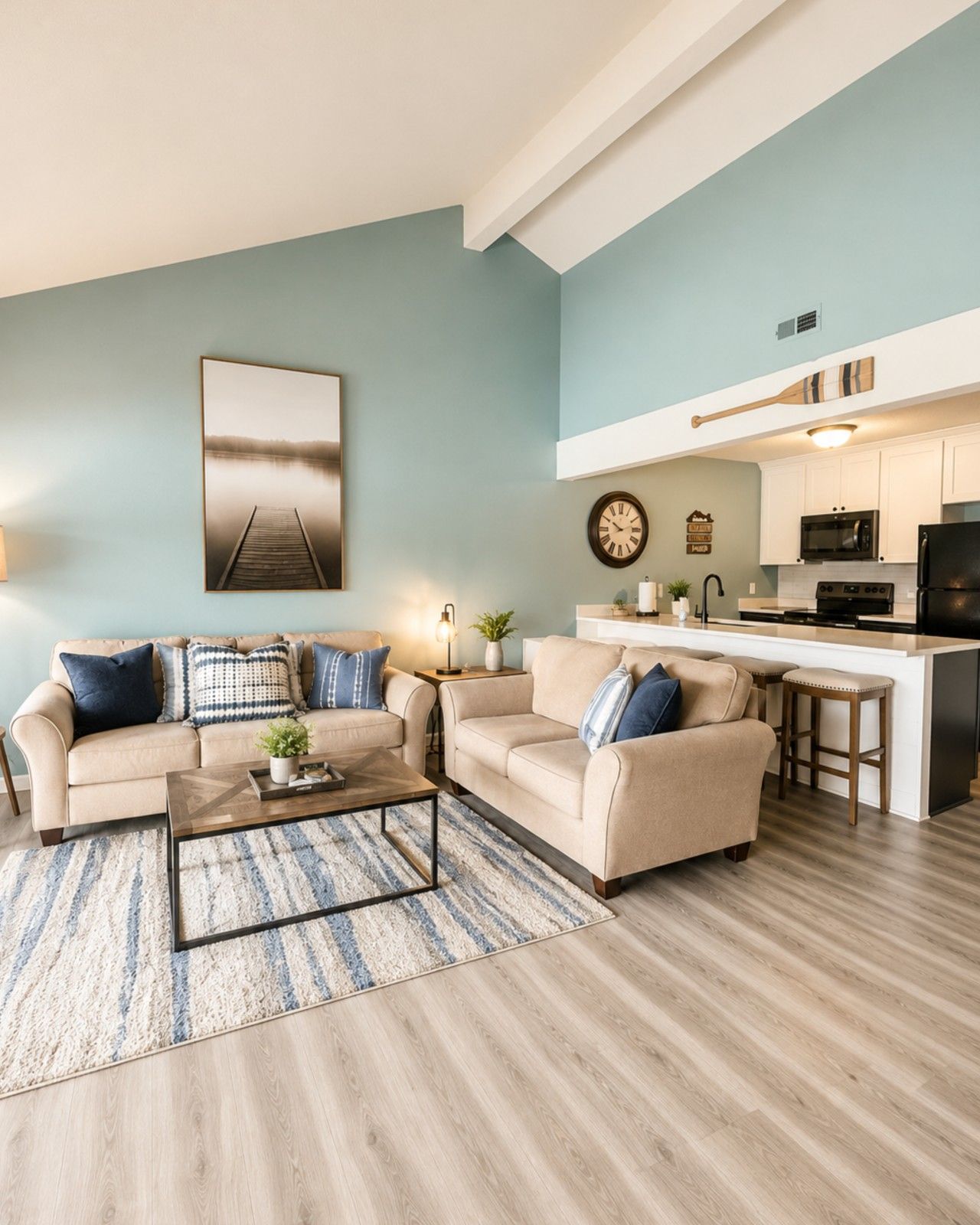 A living room with two sofas, a coffee table, and a kitchen area with a microwave and stove.