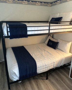 Una cama litera con una manta y almohadas azules, un suelo de madera y una pared con un detalle decorativo.