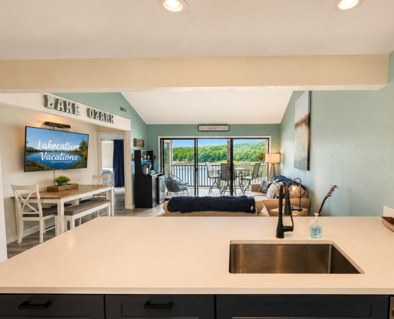 Una cocina moderna con una isla grande, un comedor y vistas a un balcón con mobiliario exterior.