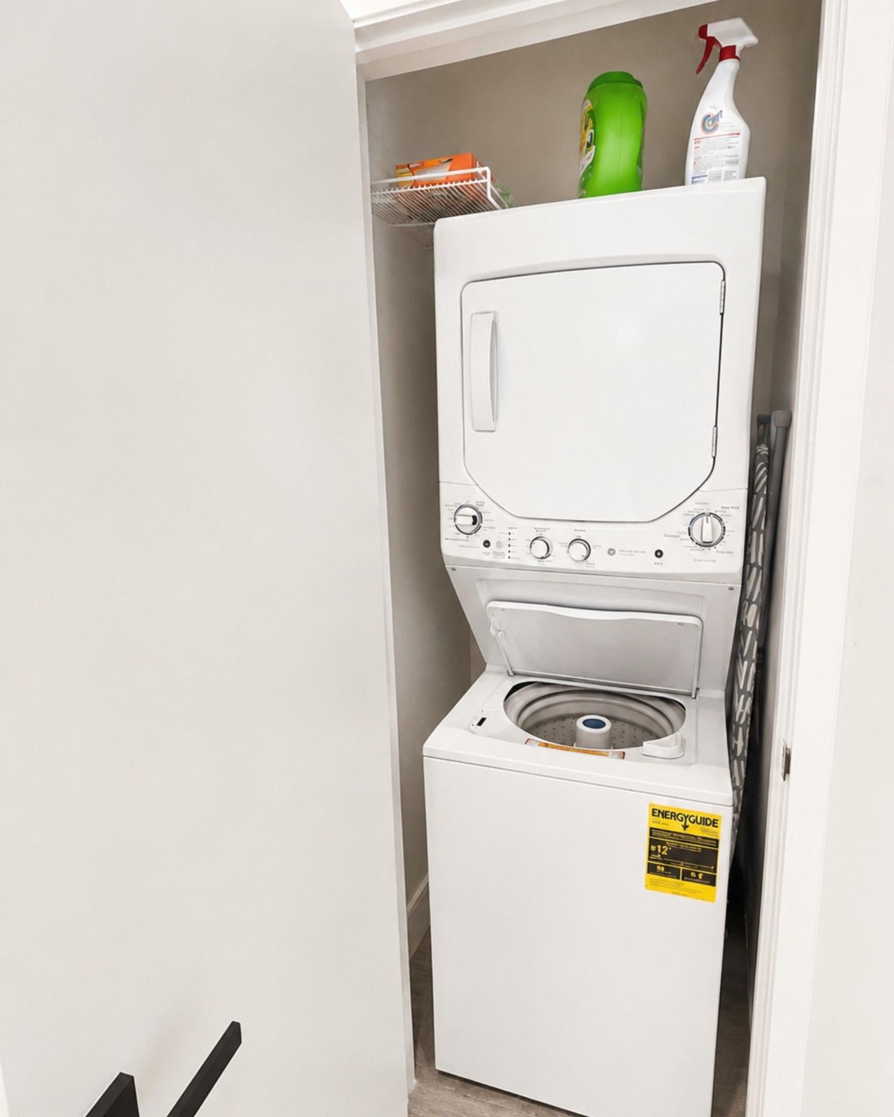 Een compact, wit was- en droogcombinatie, bevestigd aan de muur, met bedieningspaneel en een klein label aan de voorkant.