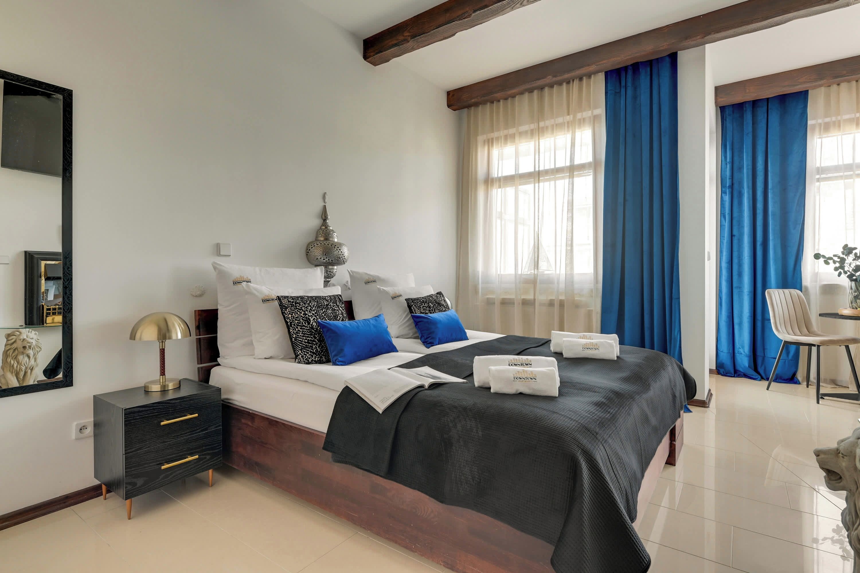 A hotel room with a bed, bedside table, lamp, and a decorative wall piece.
