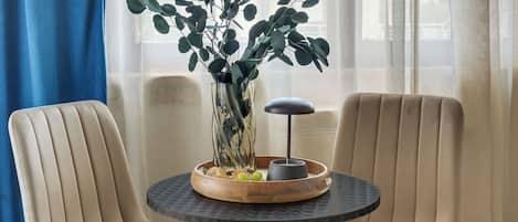 Una habitación con dos sillones color beige, una mesita redonda con un florero de follaje verde y un objeto decorativo.