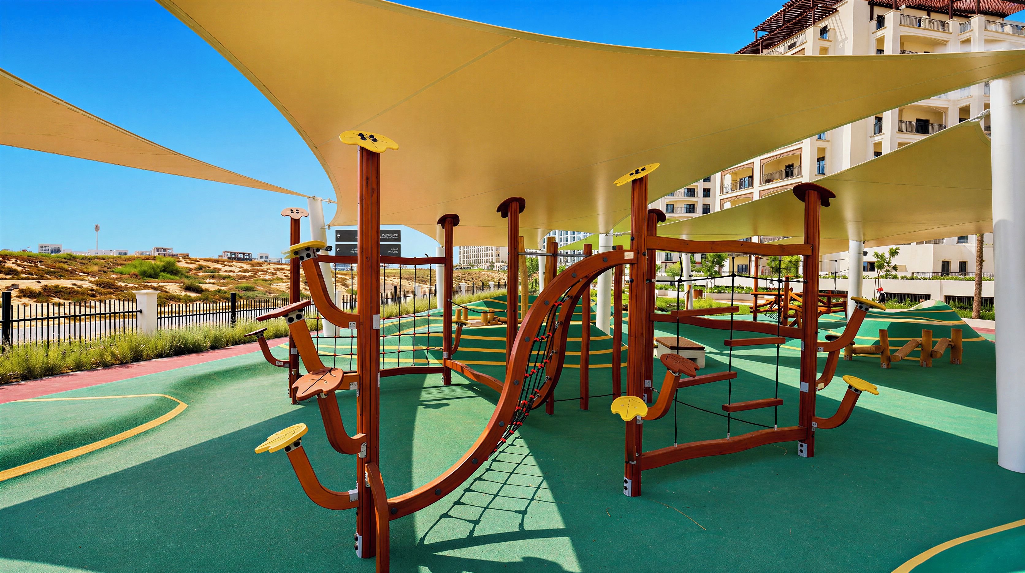 A playground with climbing structures and a covered area, surrounded by a landscaped garden and buildings in the background.