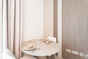 A minimalist dining area with a round table, chairs, and a set of cutlery. - Vanilla Homes Modern Studio Yas Island (Abu Dhabi)