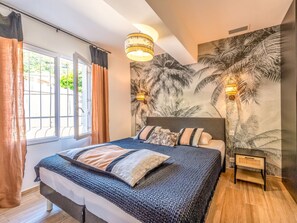 A bedroom with a bed, curtains, a wall mural, and a nightstand. - Villa in Les Issambres With Swimming Pool (Roquebrune-sur-Argens)