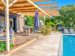 A wooden deck with a pool, outdoor seating, and a covered area with a table and chairs. - Villa in Les Issambres With Swimming Pool (Roquebrune-sur-Argens)