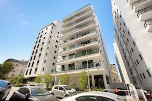 Un immeuble à plusieurs étages doté d’une architecture moderne, avec des balcons et de grandes fenêtres.