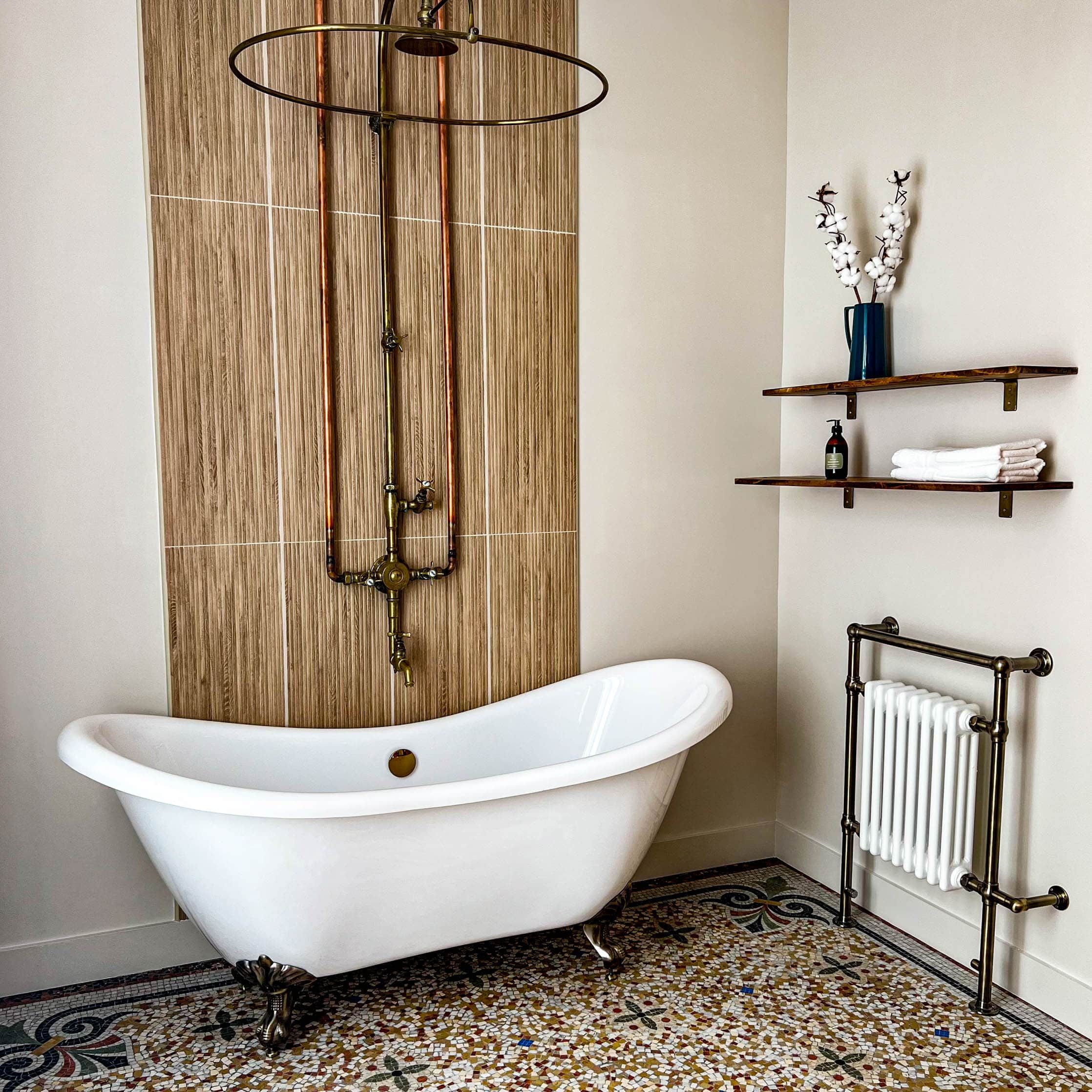 Une salle de bain avec une baignoire sur pieds, un radiateur et un sol en mosaïque.