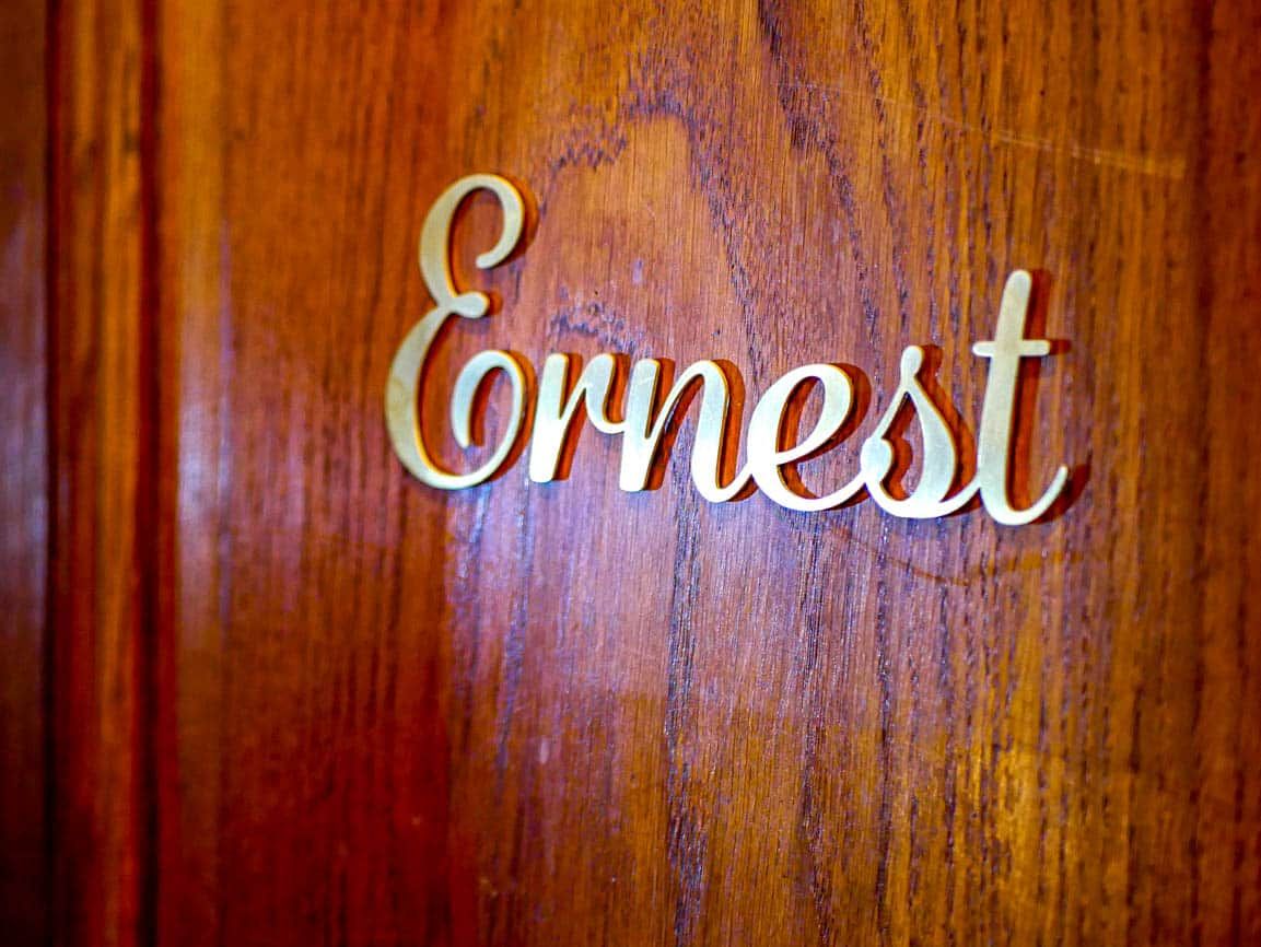 Une surface en bois sur laquelle est gravé le nom « Ernest » dans une police de caractères cursive.