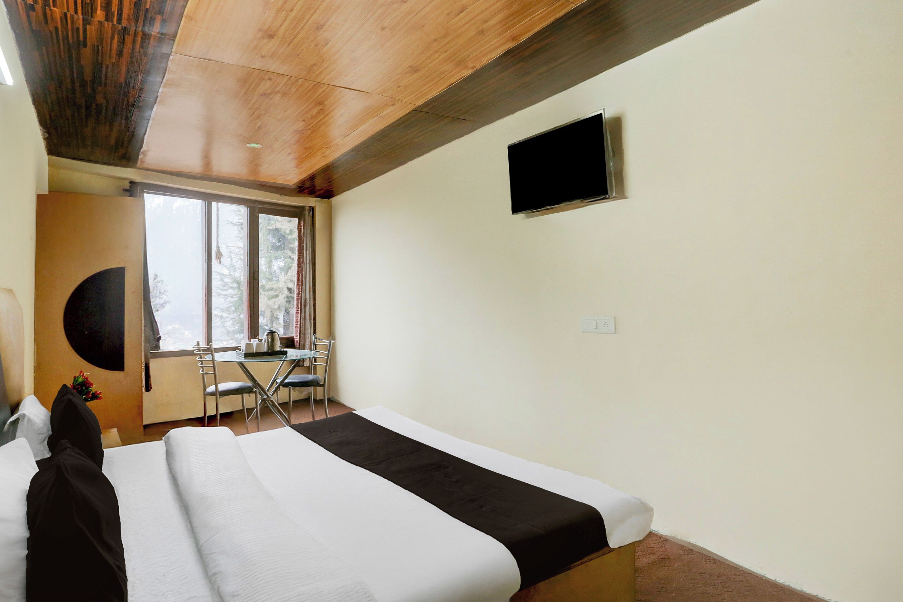 A hotel room with a bed, a desk, and a TV.