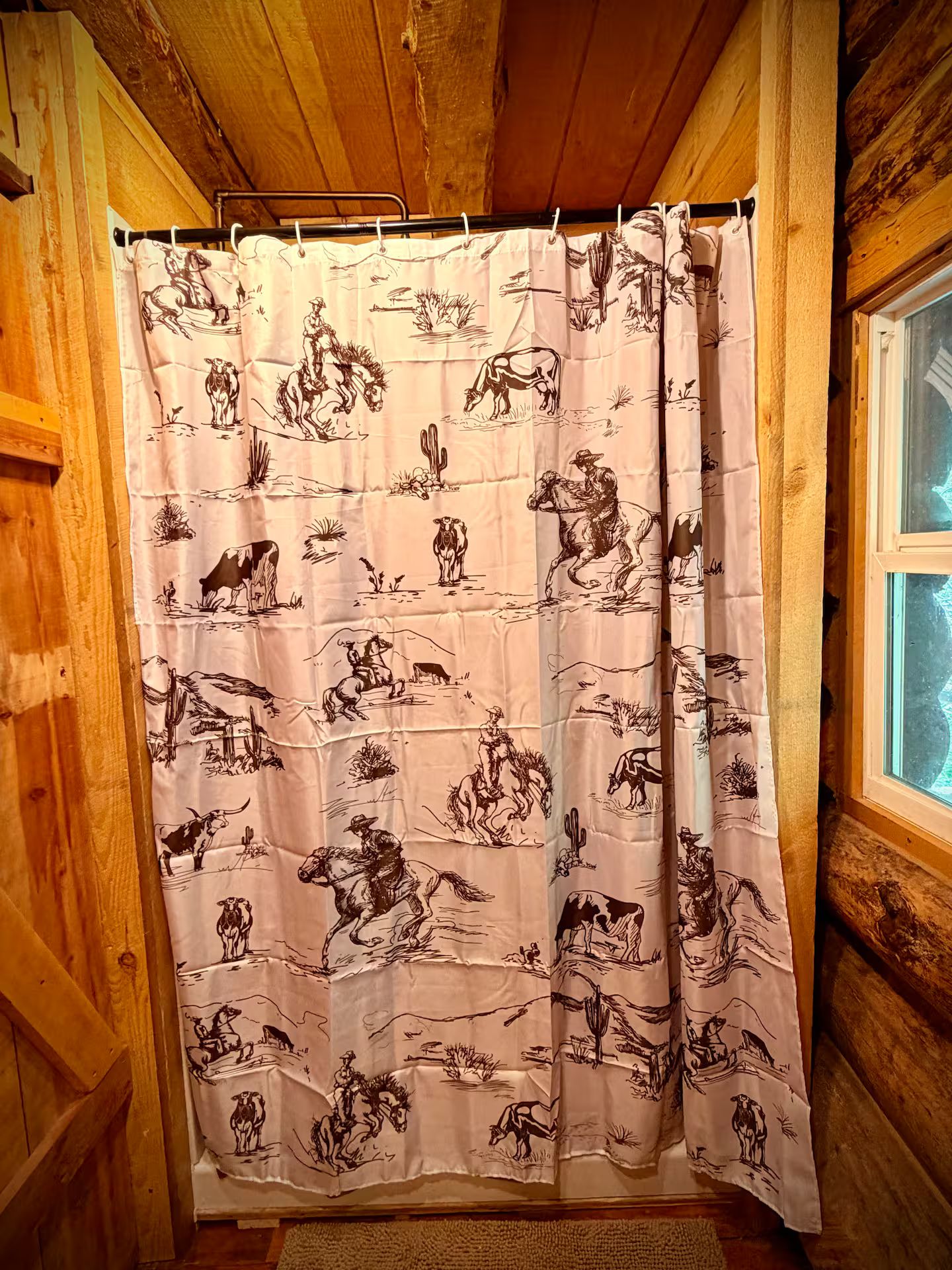 A shower curtain with a cowboy and horse pattern.