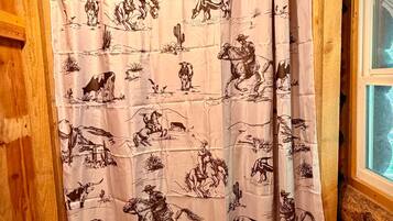 A shower curtain with a cowboy and horse pattern.