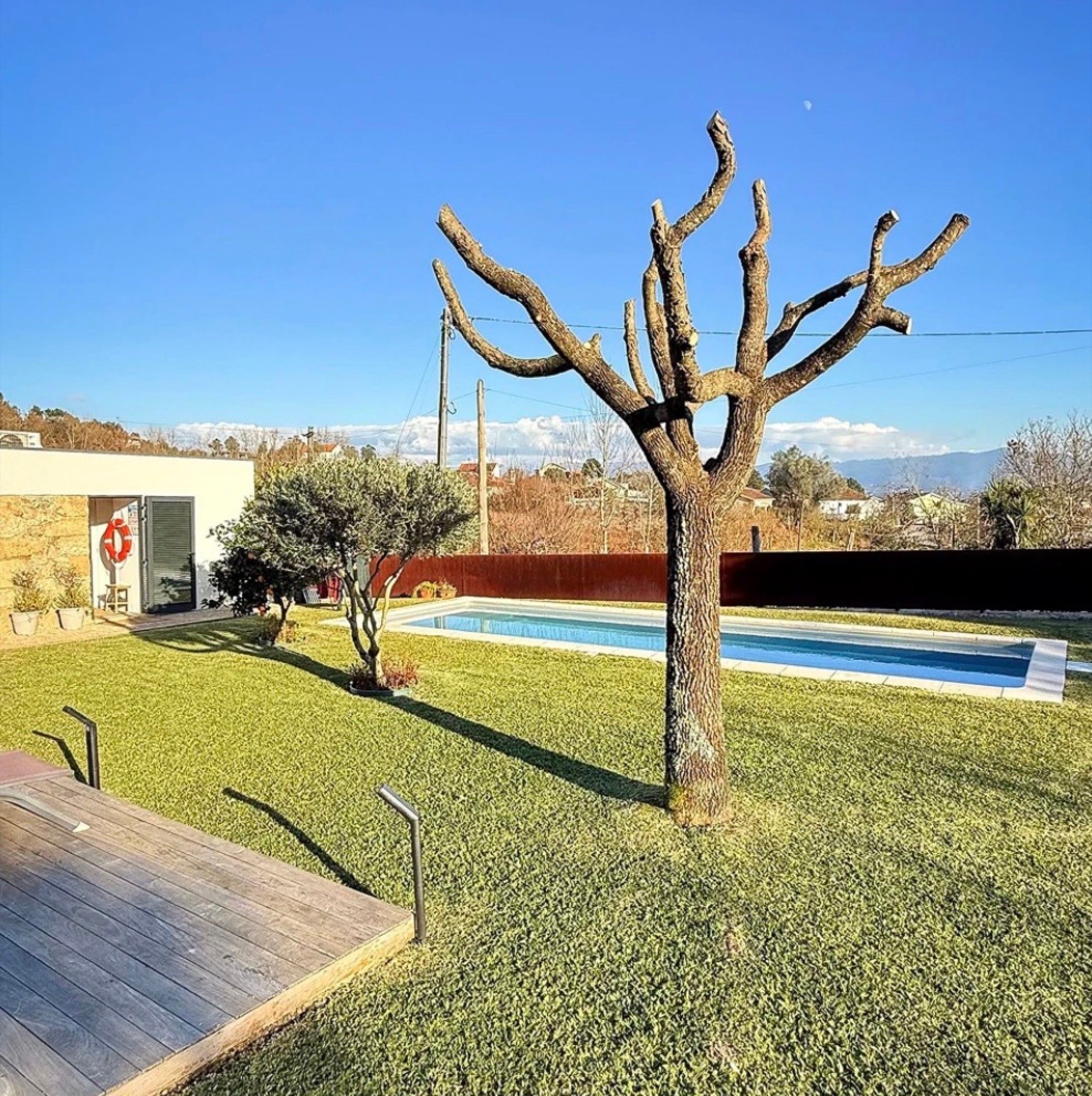 Un quartier résidentiel doté d’une piscine, d’une terrasse en bois et offrant une vue dégagée sur une chaîne de montagnes en arrière-plan.