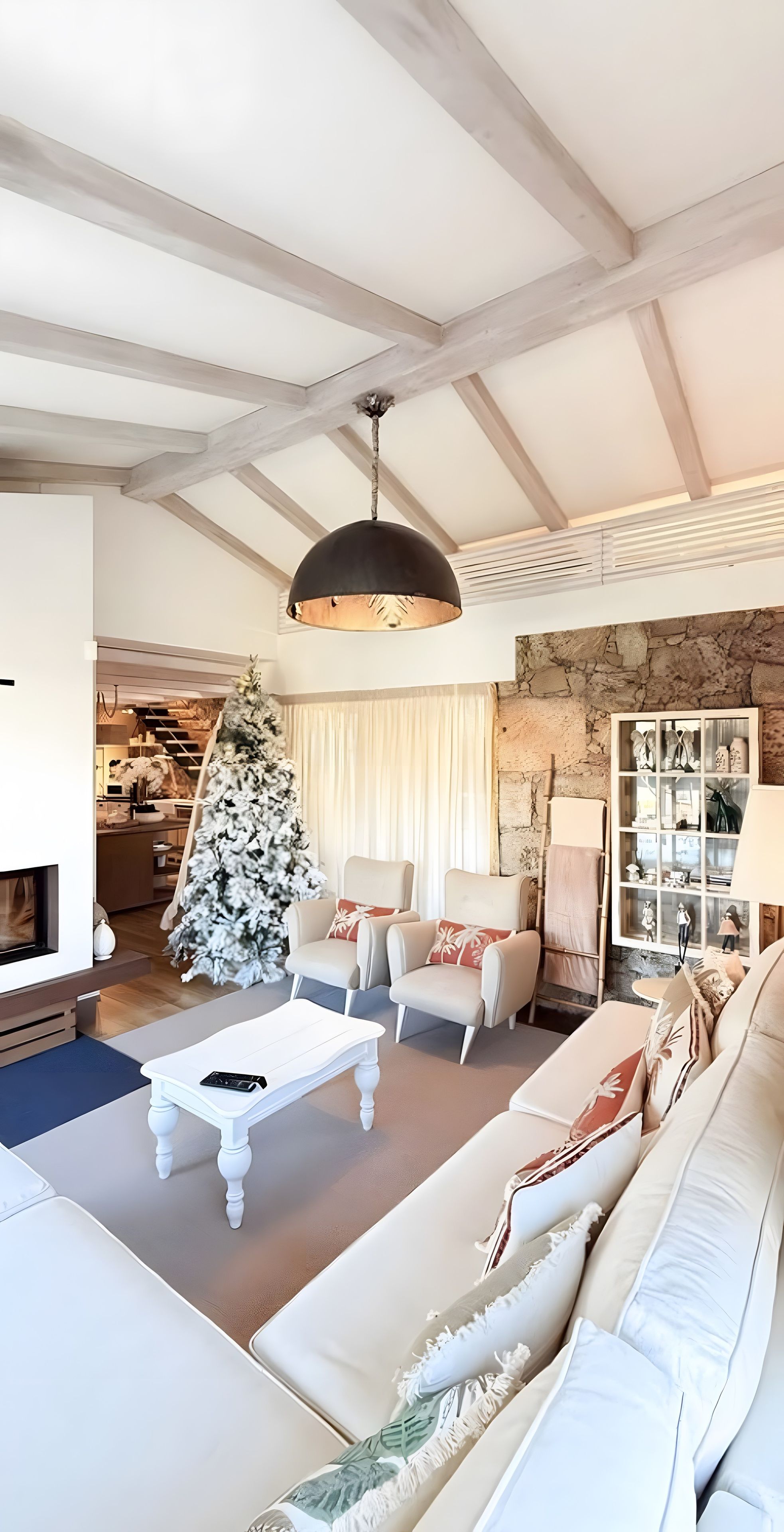 Un salon avec une cheminée, un sapin de Noël et un mur en pierre.