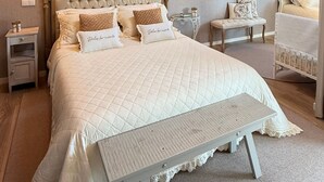 Een slaapkamer met een groot bed, een nachtkastje, een bankje, een spiegel en een dakraam.