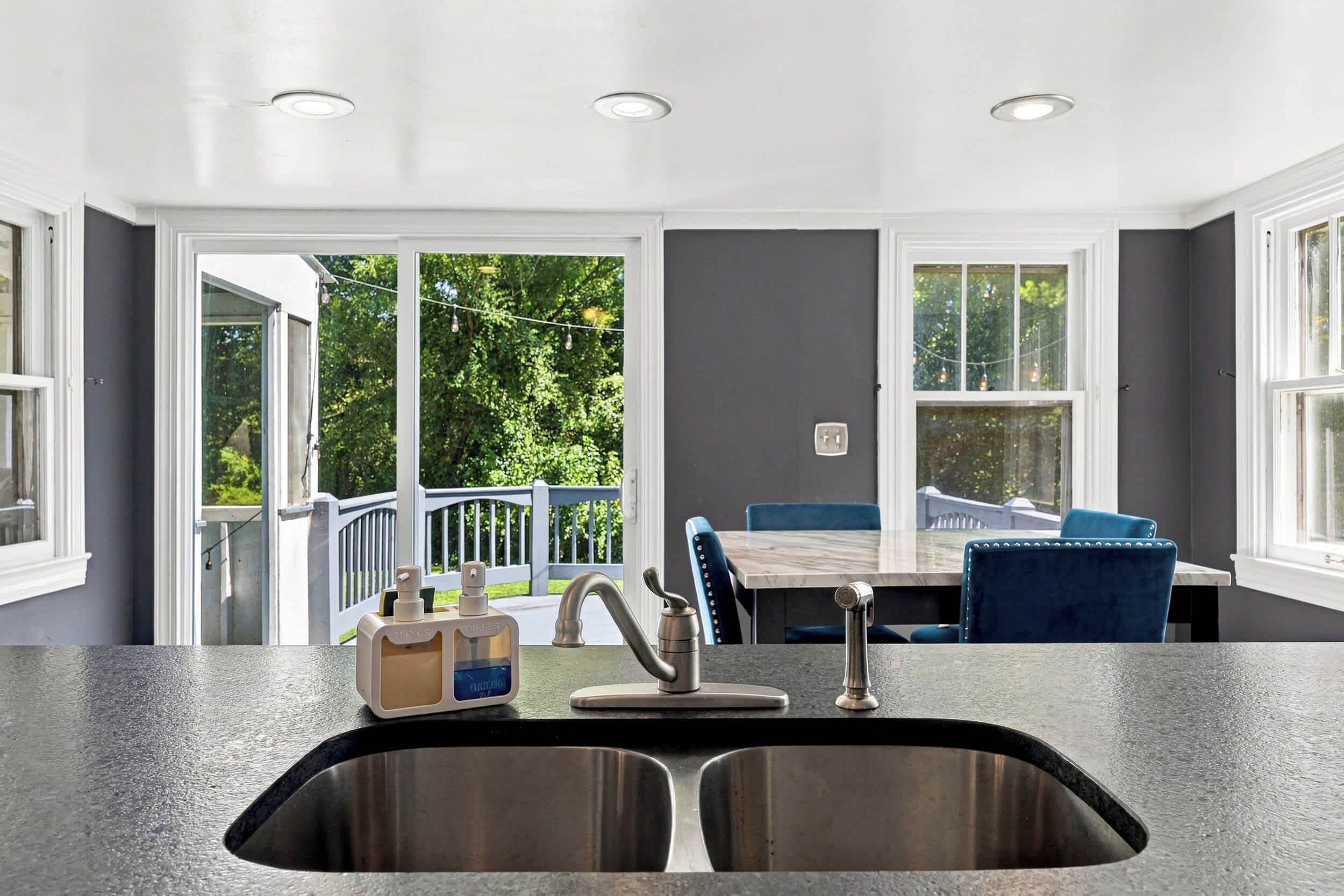 Una cocina moderna con un lavamanos de acero inoxidable, un grifo integrado y una ventana con vista a una terraza amoblada.