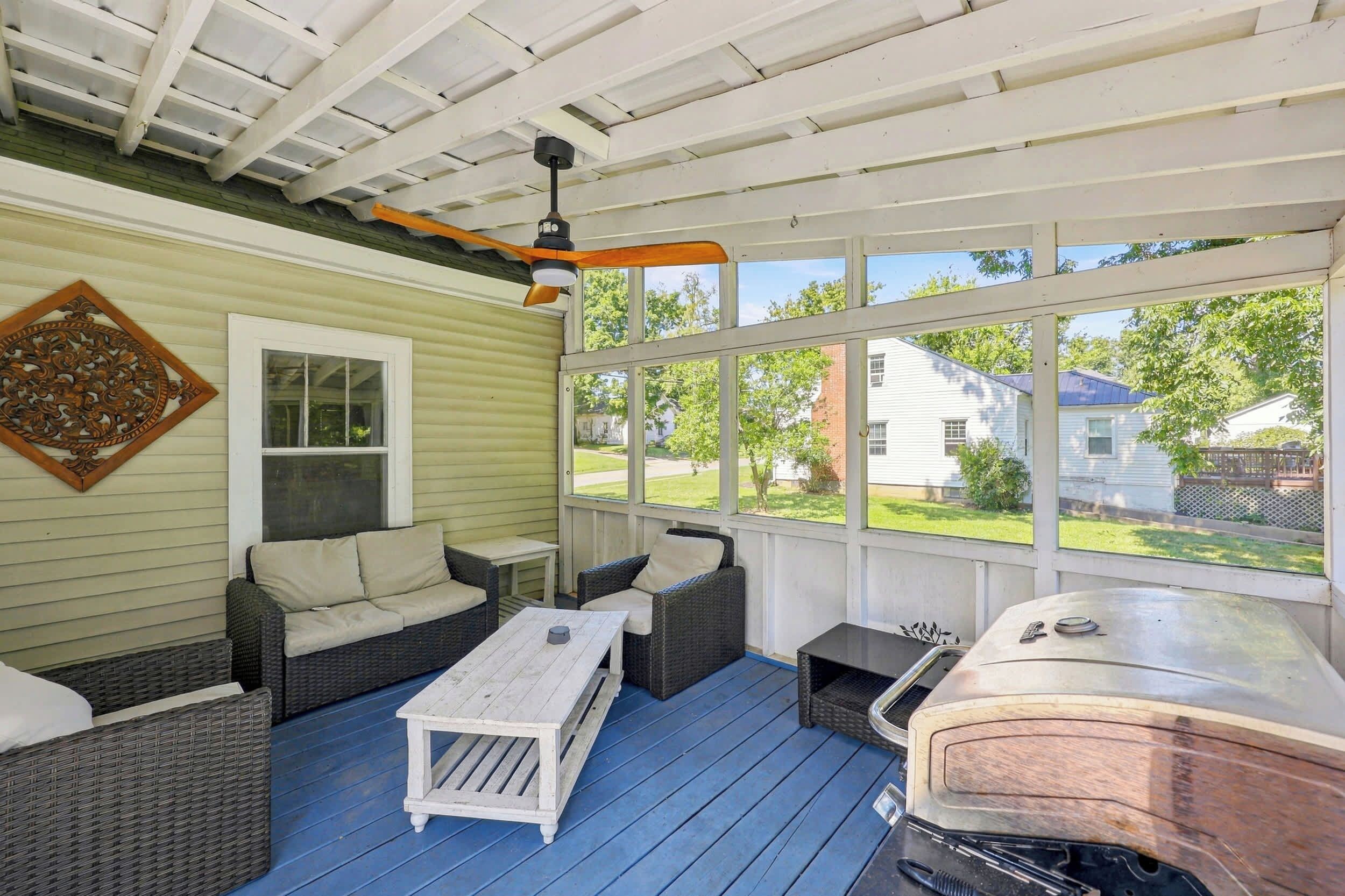 Un espace extérieur aménagé avec des meubles en osier, un barbecue et une vue sur le quartier.